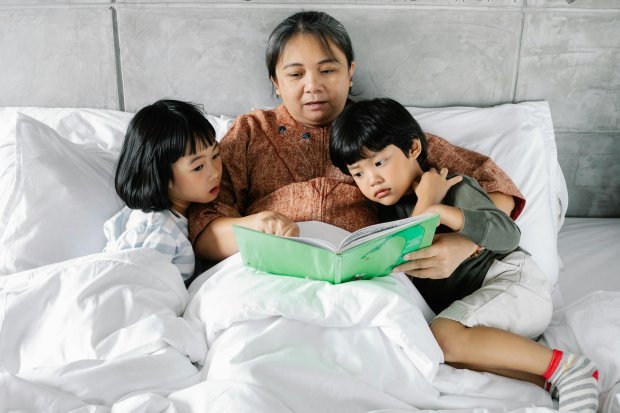 A mother in bed reading to her children